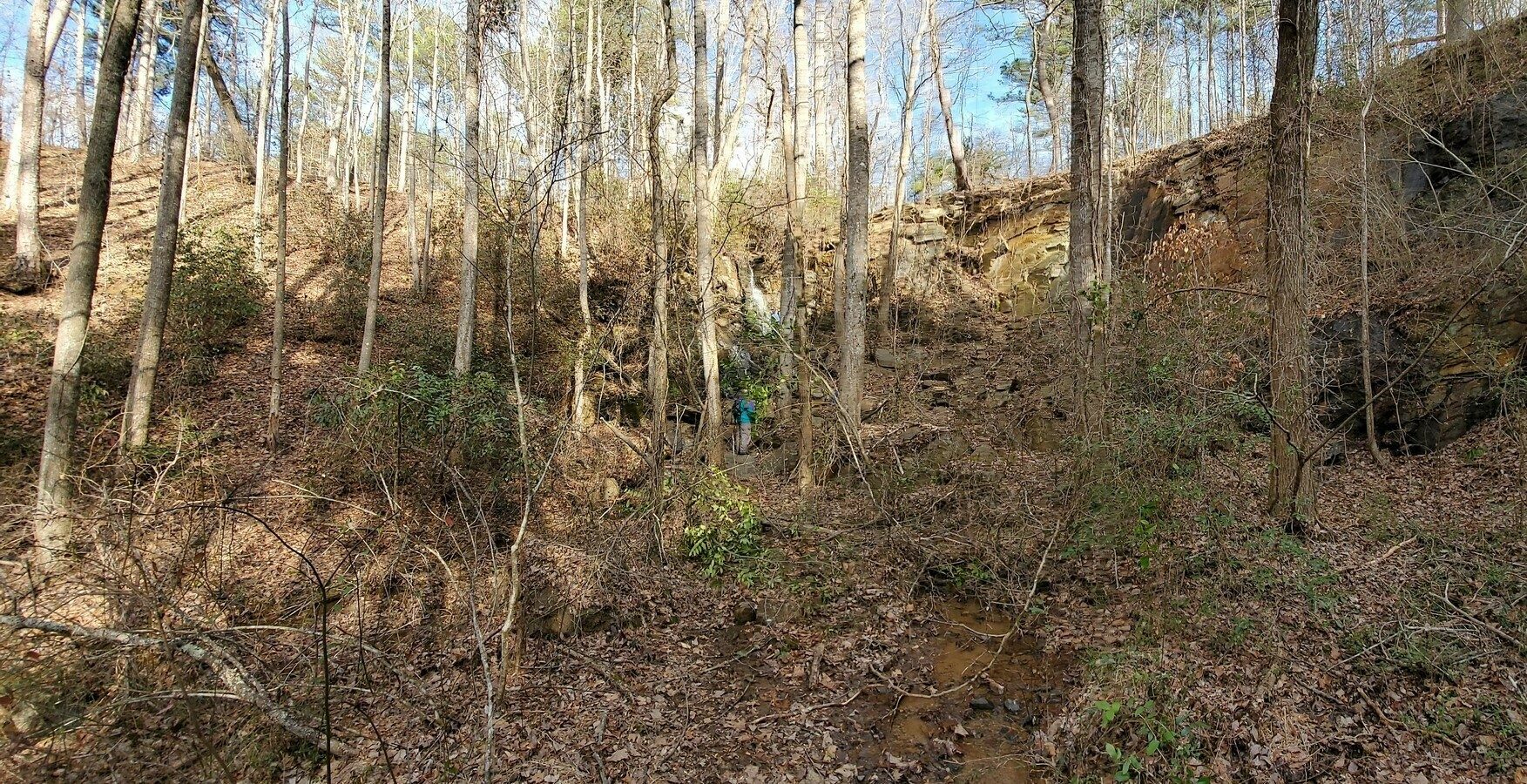 A panoramic view of the rocky cut into the hillside over which Tiny Dancer Falls flows.