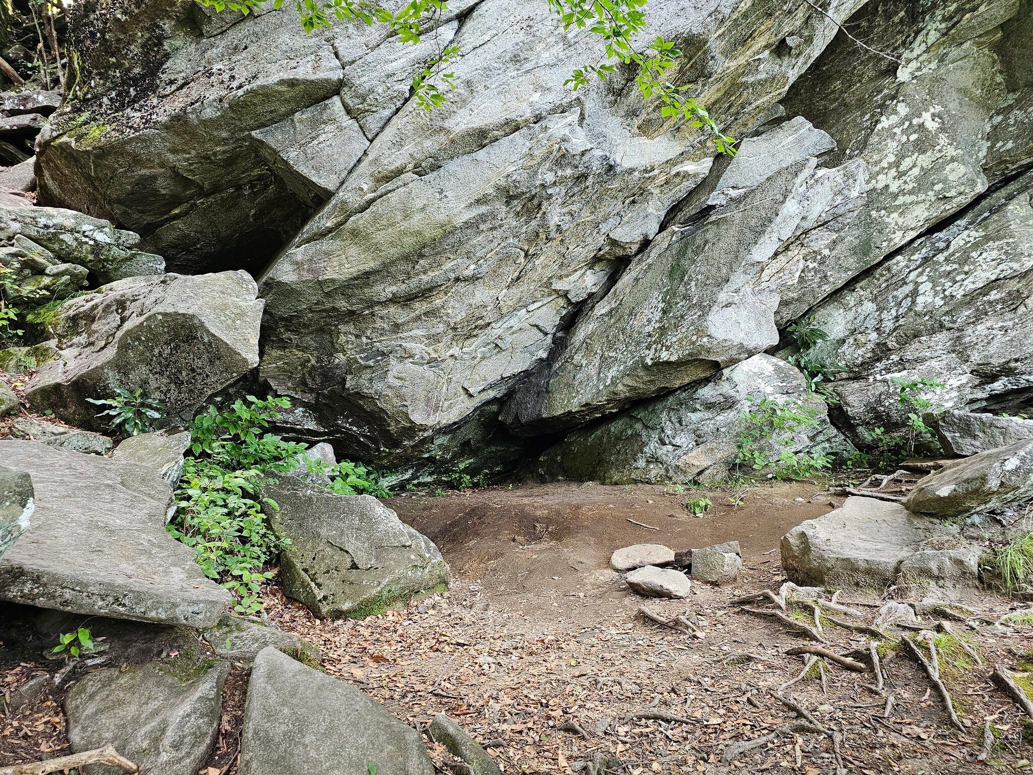 A cave/large rock overhang ~80 feet below the trail.