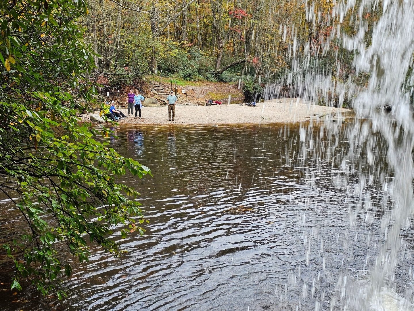 A view of the beach and fellow hikers from under the falls.