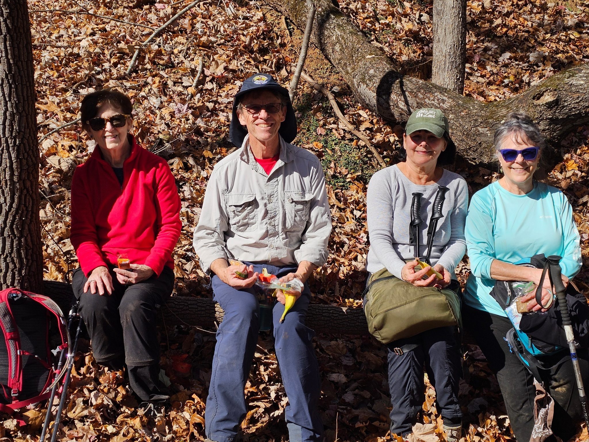 Ladies and a gentleman lunching on a log.
